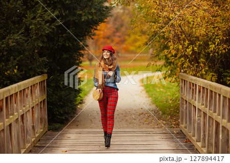 smiling modern woman in jeans shirt and red hat walking smiling modern woman in jeans shirt and red hat walking 127894417