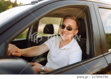 Young couple in new car is relaxing in sunset. Man has fun with girl in car at wheel Travel, tourism Young couple in new car is relaxing in sunset. Man has fun with girl in car at wheel Travel, tourism 127894790