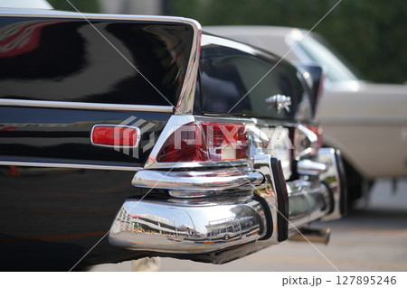 The chrome bumper of a vintage car glows with light, adding to the car classic allure and sleek design. 127895246