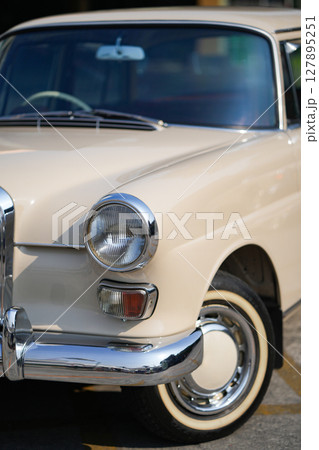The chrome bumper of a vintage car glows with light, adding to the car classic allure and sleek design. 127895251