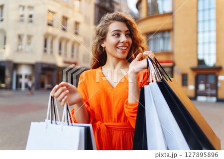 Young woman with shopping bags near mall. Purchases, shopping, lifestyle, sale concept. 127895896