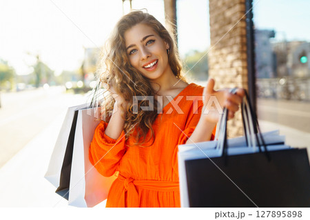 Young woman with shopping bags near mall. Purchases, shopping, lifestyle, sale concept. 127895898