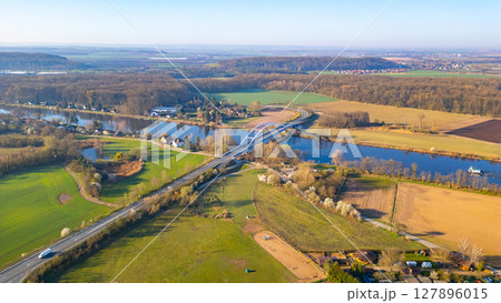 Bohumil Hrabal's Bridge elegantly stretches over the Labe River in Litol, Lysa nad Labem, surrounded by lush green fields and serene landscapes during a clear day. 127896015