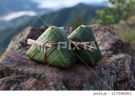 山の岩場に置かれた笹の葉に包まれた手作りおにぎり 127896061