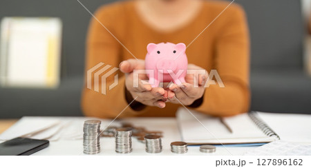 Financial Planning: Woman Holding Piggy Bank with Coins 127896162