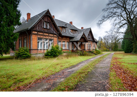 Abandoned manor house with overgrown garden in autumn 127896394