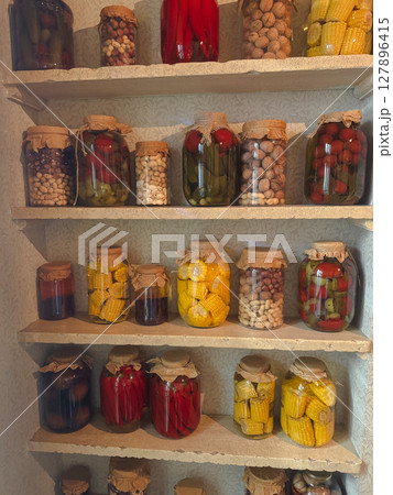 Preserved vegetables and fruits on display in glass jars in a kitchen Preserved vegetables and fruits on display in glass jars in a kitchen 127896415