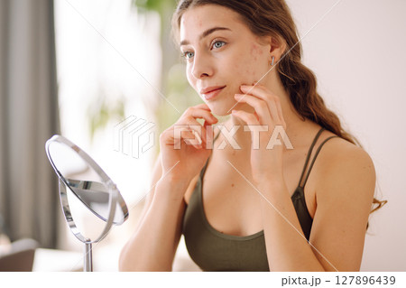 Woman worry about her face when she saw the problem of acne occur by a mini mirror. Pimples, acne Woman worry about her face when she saw the problem of acne occur by a mini mirror. Pimples, acne 127896439