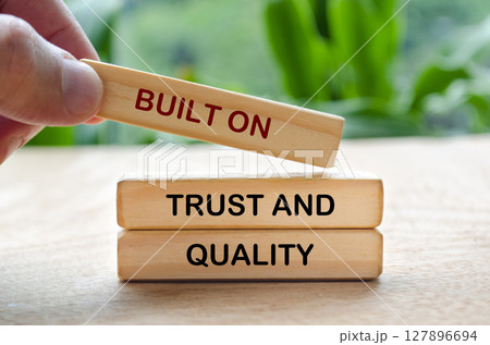 Hand placing wooden block that says Built On Trust And Quality text on Quality Hand placing wooden block that says Built On Trust And Quality text on Quality 127896694