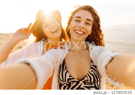 Two pretty friends women making selfie on beach, light and bright summer colors. Friends together Two pretty friends women making selfie on beach, light and bright summer colors. Friends together 127897019