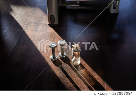 Pair of dumbbells and water sport bottle on floor of modern fitness club Pair of dumbbells and water sport bottle on floor of modern fitness club 127897054