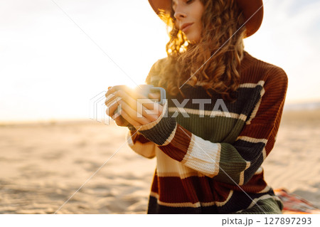 Lonely romantic woman drinking coffee looking at sunset at picnic on the beach. Lifestyle concept. Lonely romantic woman drinking coffee looking at sunset at picnic on the beach. Lifestyle concept. 127897293