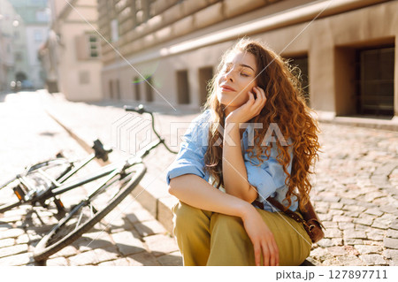 Portrait of smiling woman sitting next to bike on street city. Travel, weekend and lifestyle concept 127897711