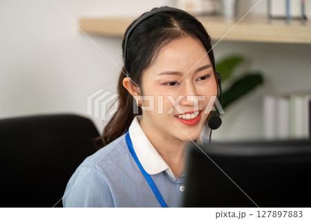 Customer Service Representative at Work. Engaged female agent smiling while assisting clients on a call. 127897883