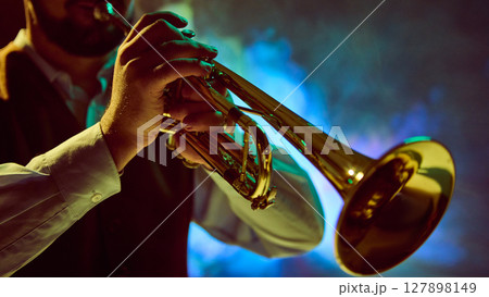Music performance with musician playing trumpet against vibrant stage lighting backdrop 127898149