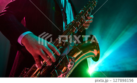 Jazz musician performing with saxophone under vibrant stage lights 127898156