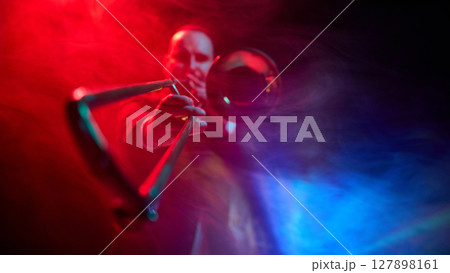 Musician playing trombone on stage with dramatic red and blue lighting effects 127898161