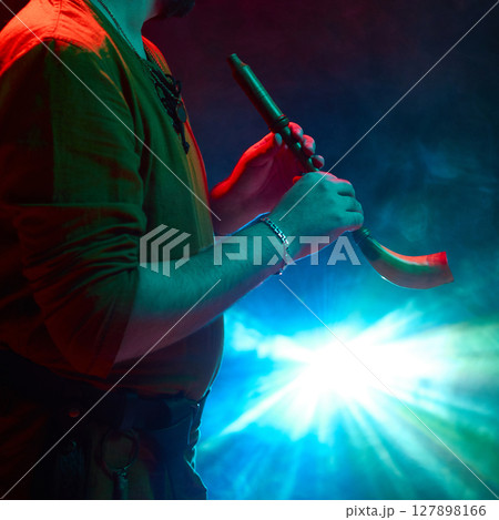 Musician playing traditional horn in vibrant stage light atmosphere 127898166