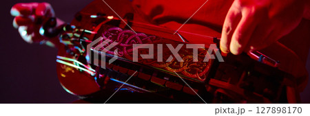 Close-up of hands playing ornate hurdy-gurdy under dramatic red lighting Close-up of hands playing ornate hurdy-gurdy under dramatic red lighting 127898170