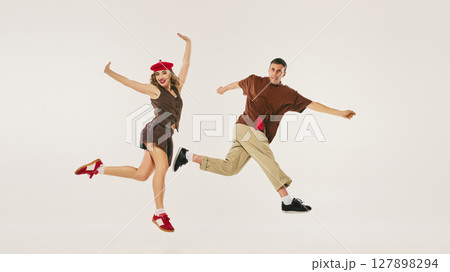 Energetic retro dancers performing lindy hop routine with vintage outfits on neutral background Energetic retro dancers performing lindy hop routine with vintage outfits on neutral background 127898294