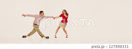 Couple joyfully performing retro lindy hop dance in vintage fashion against plain background. Banner Couple joyfully performing retro lindy hop dance in vintage fashion against plain background. Banner 127898331