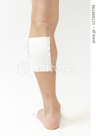 湿布を貼った男性の脚　白バック 127898798