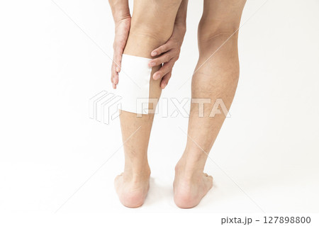 湿布を貼った男性の脚　白バック 127898800