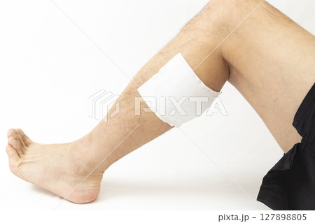 湿布を貼った男性の脚　白バック 127898805