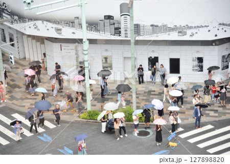 雨の銀座四丁目歩行者天国で傘をさして歩く人々 127898820