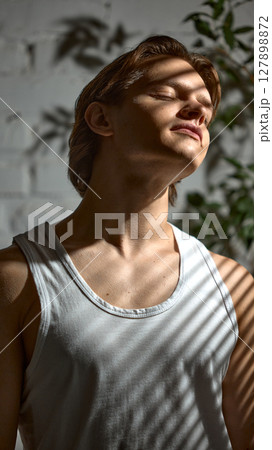 Glam shadows. Young man in partial light, shadow lines from blinds across his face. 127898872