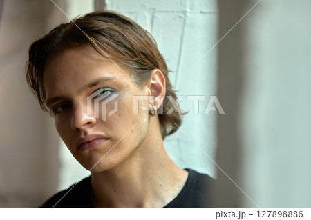 Bold dopamine. Young man with gloss and icy-toned eyeshadow. Confident and bold. Bold dopamine. Young man with gloss and icy-toned eyeshadow. Confident and bold. 127898886
