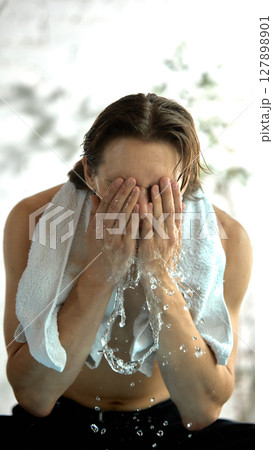 Skin-realism. Man splashes water on his face, droplets glisten on his skin. 127898901