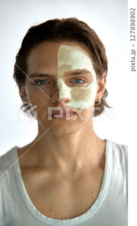 Natural beauty. Clay mask covers half the young man face, dramatic texture in detail. 127898902