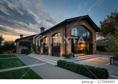 Modern office building with large windows, built in a renovated former industrial building with exposed brick walls at sunset 127899983