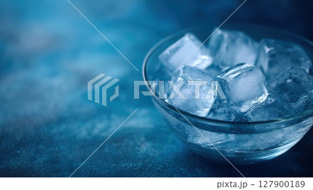 透明なガラスボウルに入った氷の塊・青い背景が涼しさを演出する写真 127900189
