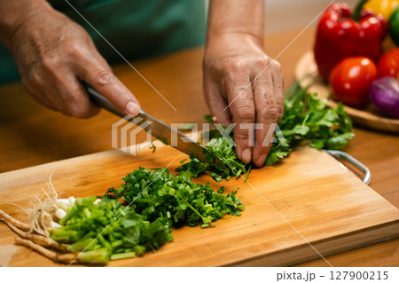 Asian man's hands chopping coriander in the kitchen Asian man's hands chopping coriander in the kitchen 127900215
