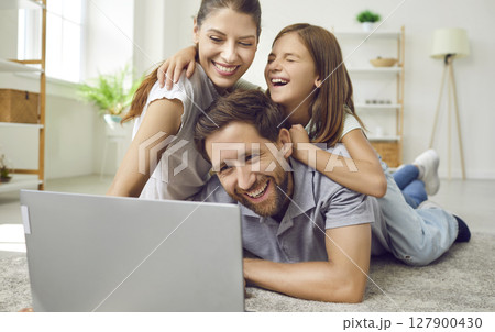 Portrait of happy loving family using laptop while spending time together at home in living room. Portrait of happy loving family using laptop while spending time together at home in living room. 127900430