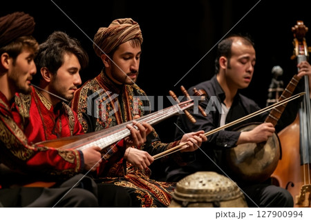 Group of four musicians wearing traditional clothing are playing folk instruments and performing on stage 127900994
