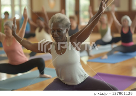 Senior african american woman is practicing yoga in a warrior position with her class 127901129