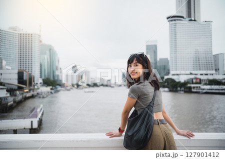 Happy solo southeast asian woman teenager blogger, world travel explorer. Wait for express boat on Chao Phraya river in Bangkok, local cultural tourism experience concept in Thailand, Asia Happy solo southeast asian woman teenager blogger, world travel explorer. Wait for express boat on Chao Phraya river in Bangkok, local cultural tourism experience concept in Thailand, Asia 127901412