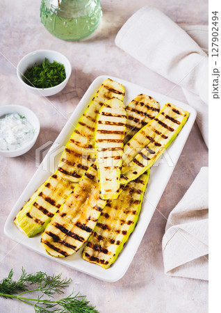 Delicious grilled vegetable zucchini on a plate on the table vertical view 127902494