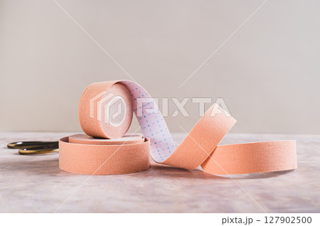 Neutral colored kinesio tapes for face lifting and scissors on the table 127902500