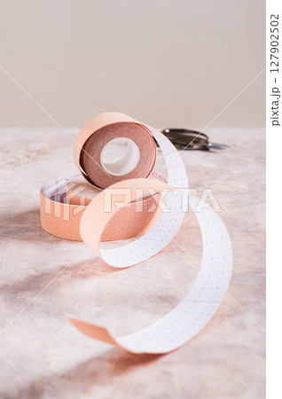 Modern trend against aging and wrinkles kinesio tape in a roll on the table vertical view 127902502