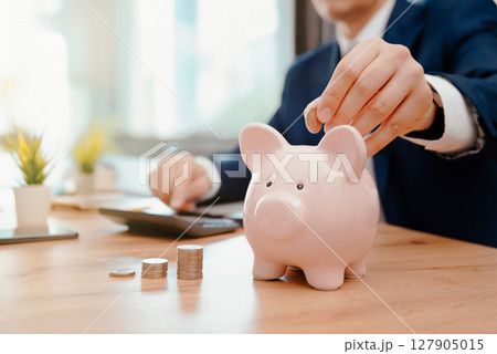 Savings concept with man putting coin Savings concept with man putting coin 127905015