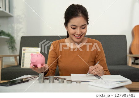 Budgeting and Savings: Young Woman with Piggy Bank 127905483