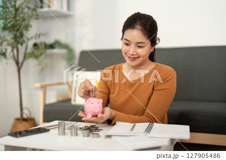 Financial Empowerment: Young Woman Saving Money with Piggy Bank 127905486