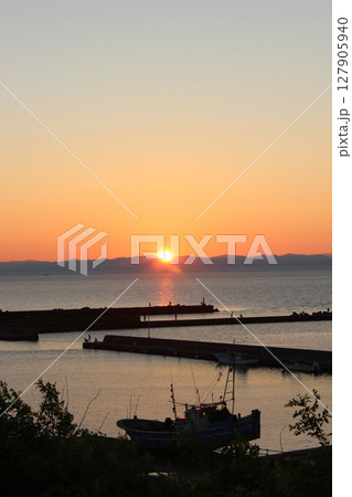 夕日が沈む海と小さな港_1 127905940