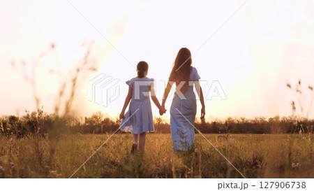 mother daughter walking field sunset holding hands, happy family, child loves mother, holding parent hand sunset, happy people nature, mother daughter outdoors, family vacation nature, walking 127906738