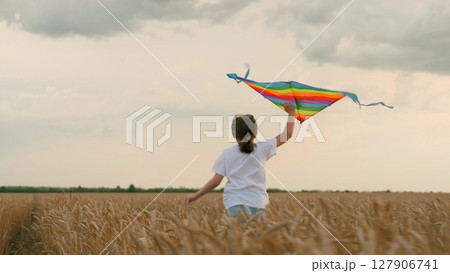 concept happy childhood. Little girl schoolgirl, fly kites into sky, field wheat sunset. child happily runs through field wheat. Children kite game. concept child dream. Children imagination dream concept happy childhood. Little girl schoolgirl, fly kites into sky, field wheat sunset. child happily runs through field wheat. Children kite game. concept child dream. Children imagination dream 127906741