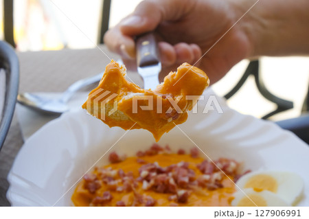 man about to eat a piece ob bread dipped in salmorejo 127906991